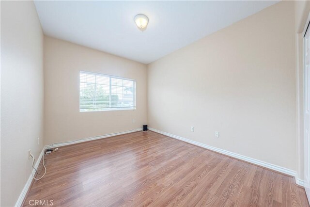 spare room featuring light wood-style floors and baseboards