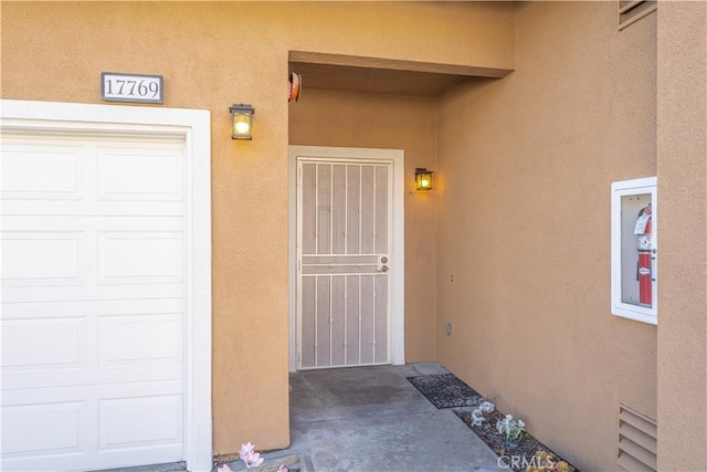 entrance to property featuring stucco siding and a garage
