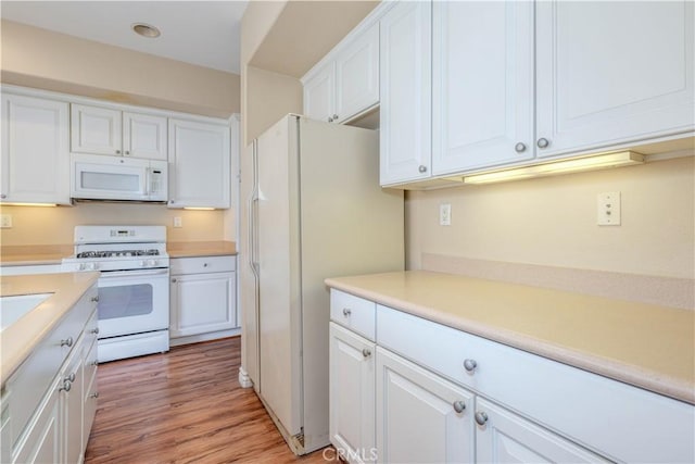 kitchen featuring white appliances, white cabinetry, light countertops, and light wood-style flooring