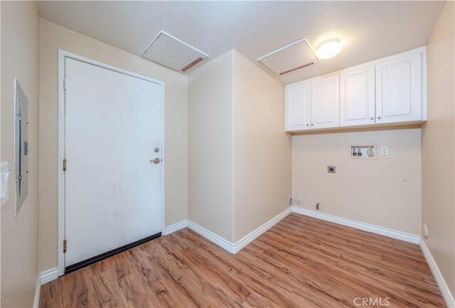 clothes washing area featuring hookup for a washing machine, cabinet space, electric dryer hookup, attic access, and light wood-style flooring