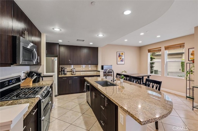 kitchen featuring appliances with stainless steel finishes, a sink, light tile patterned floors, an island with sink, and recessed lighting