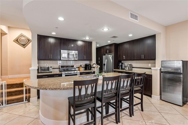 46 Beacon Way, Aliso Viejo, CA 92656 - kitchen featuring stainless steel appliances, a sink, light tile patterned flooring, a breakfast bar area, and backsplash