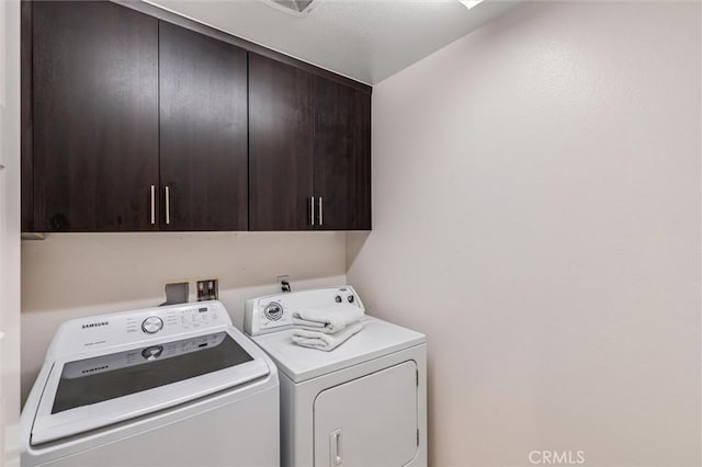 washroom featuring cabinet space and washer and clothes dryer
