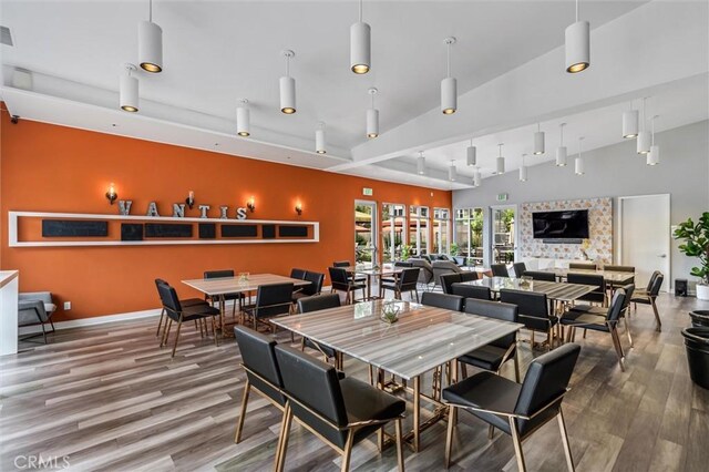 dining area with wood finished floors, track lighting, and baseboards