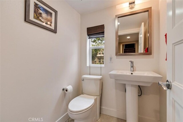 half bathroom with baseboards and toilet