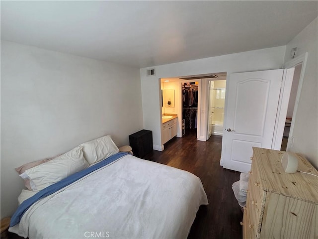 bedroom featuring dark wood-style floors, a spacious closet, baseboards, connected bathroom, and a closet
