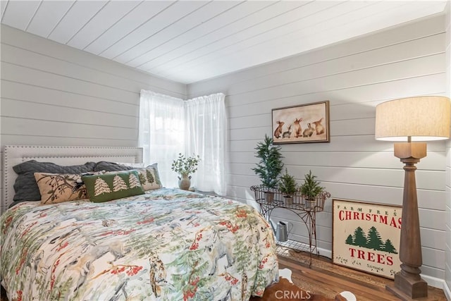 bedroom with wood finished floors and wood walls
