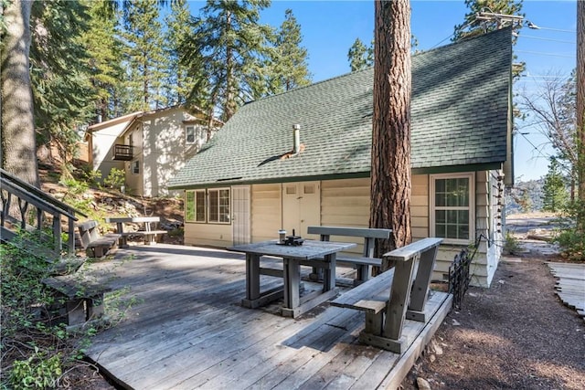 back of property featuring roof with shingles and a wooden deck