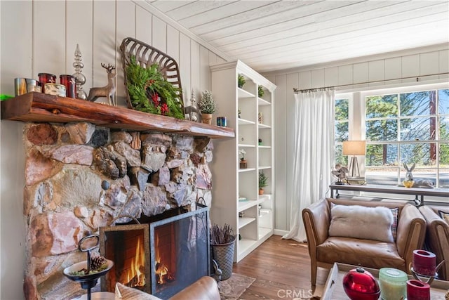 living area featuring a stone fireplace, wood finished floors, and wood ceiling