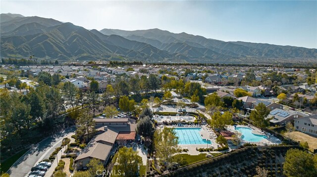 aerial view of property and surrounding area with a pool, nearby suburban area, and a mountainous background