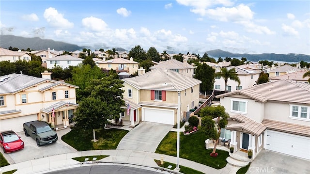 view of front of house with a residential view, driveway, an attached garage, and a mountain view