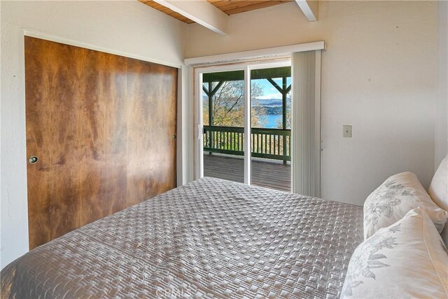 bedroom with access to exterior, beamed ceiling, a water view, wooden ceiling, and a closet