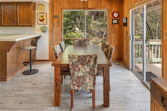 dining area featuring wood tiled floors, wooden walls, plenty of natural light, and baseboards