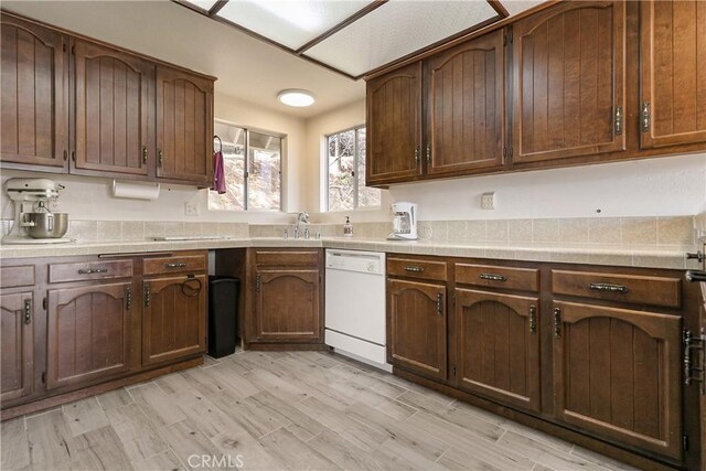 kitchen featuring dishwasher, light wood-type flooring, and a sink