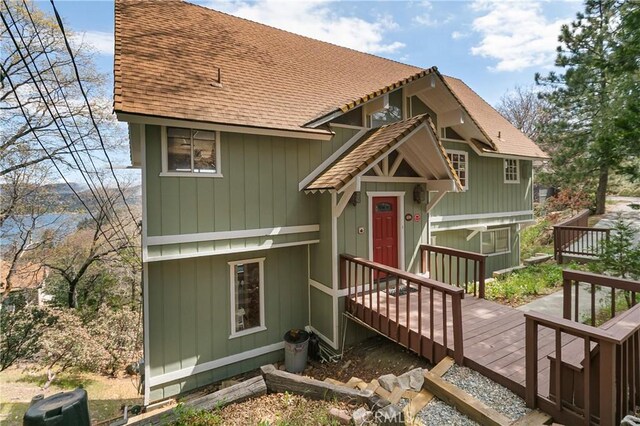 view of front facade featuring a shingled roof and a deck