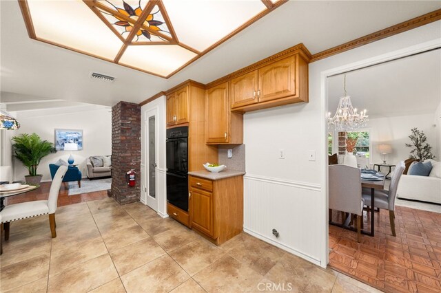 kitchen with open floor plan, a chandelier, light countertops, wainscoting, and brown cabinetry