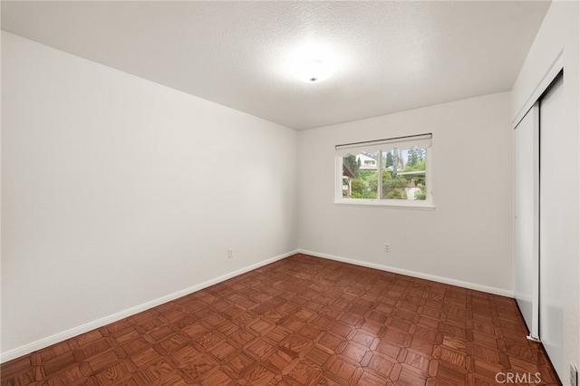 unfurnished bedroom featuring a closet, baseboards, and a textured ceiling