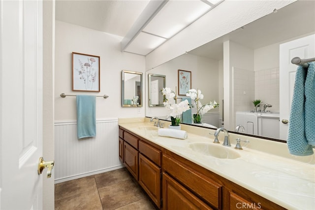bathroom featuring a wainscoted wall, double vanity, a tub, and toilet