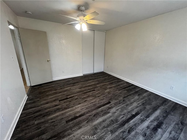 spare room featuring dark wood-type flooring, a ceiling fan, baseboards, and a smoke detector