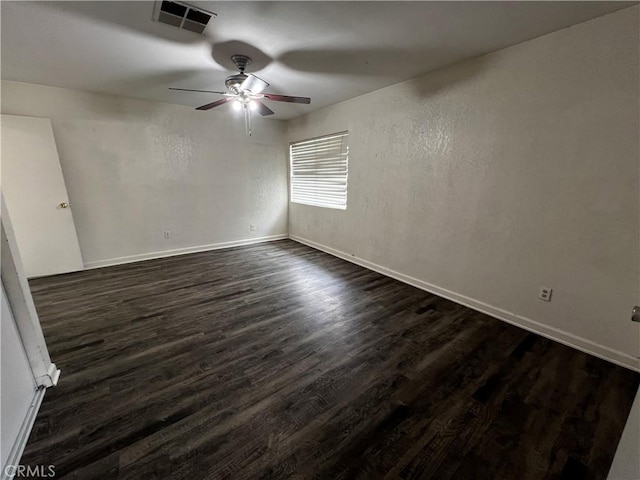 spare room with a ceiling fan, dark wood-type flooring, and baseboards