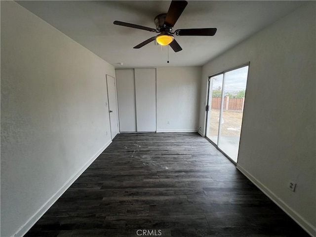unfurnished room featuring baseboards, dark wood-type flooring, and a ceiling fan