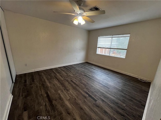 empty room with dark wood finished floors, ceiling fan, and baseboards