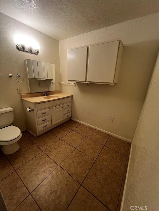 half bathroom featuring tile patterned floors, a textured ceiling, toilet, vanity, and baseboards