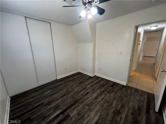 unfurnished bedroom with wood finished floors, baseboards, a closet, and a ceiling fan