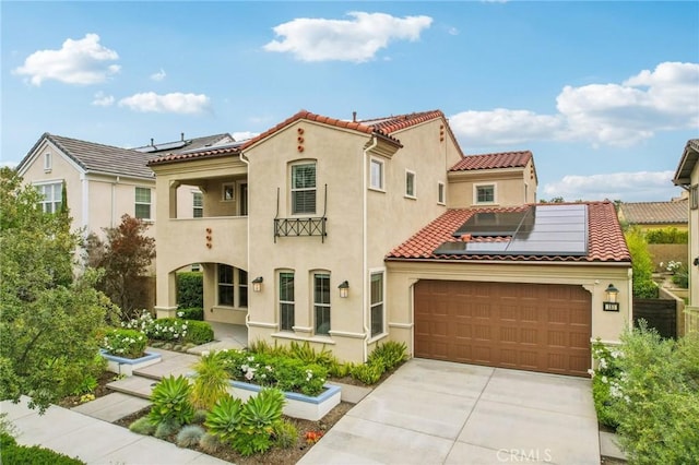 mediterranean / spanish-style house featuring roof mounted solar panels, stucco siding, concrete driveway, and a tile roof