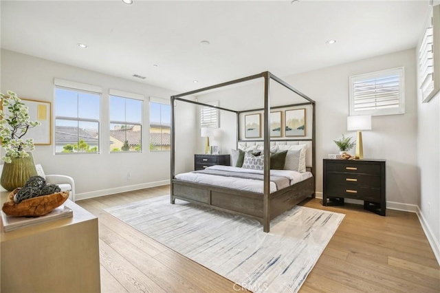 bedroom with multiple windows, light wood finished floors, baseboards, and recessed lighting