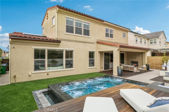 rear view of property with outdoor lounge area, a wooden deck, stucco siding, and a tiled roof