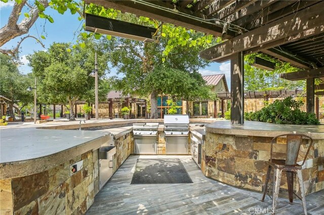 view of patio featuring area for grilling, exterior kitchen, exterior bar, and a wooden deck