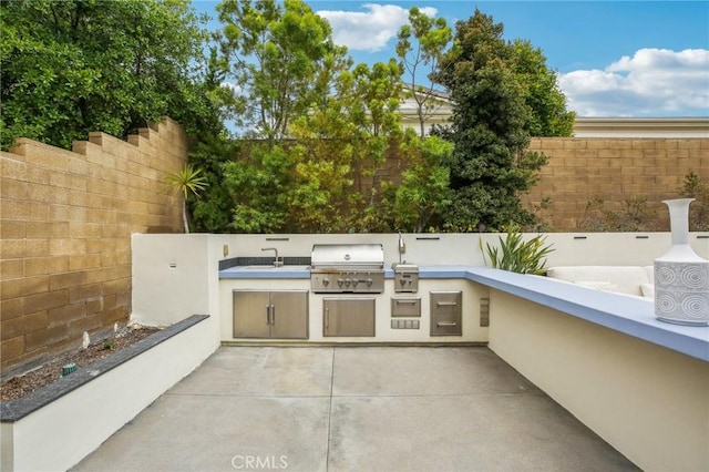 view of patio featuring area for grilling, fence, a sink, and an outdoor kitchen