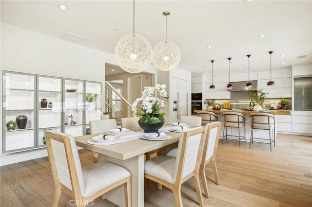 dining room with light wood finished floors, stairs, and recessed lighting