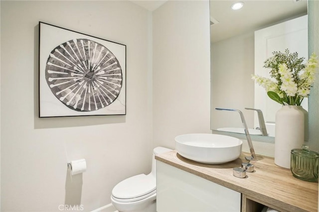 bathroom featuring toilet, vanity, recessed lighting, and baseboards