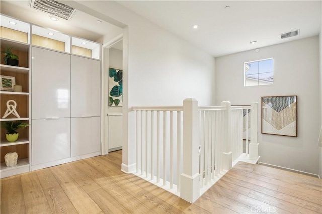 hallway with an upstairs landing and light wood finished floors