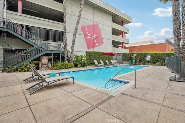 view of pool featuring stairway, a patio area, and fence
