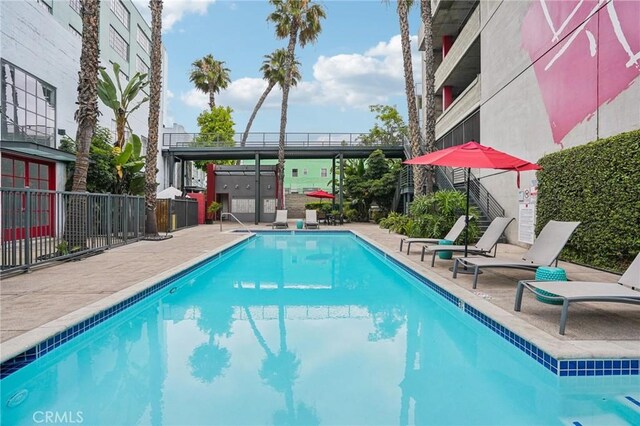 community pool featuring stairway, a patio area, and fence