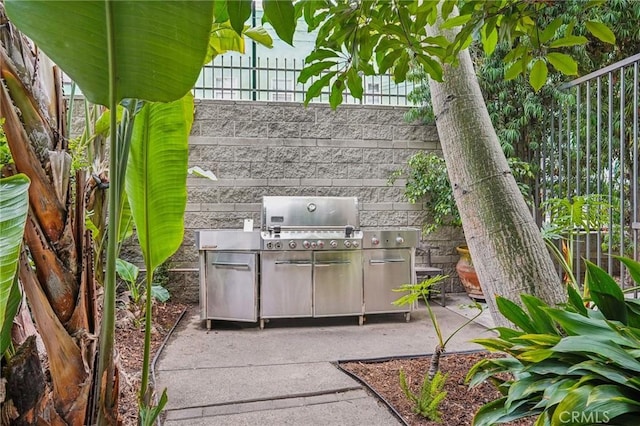 view of patio featuring fence, exterior kitchen, and area for grilling