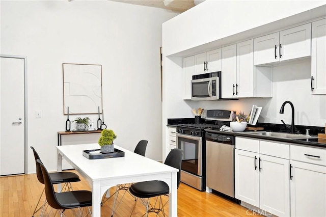 kitchen featuring stainless steel appliances, a sink, light wood-style flooring, and a breakfast bar