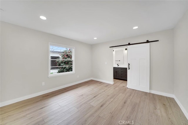 212 La Paloma, San Clemente, CA 92672 - unfurnished bedroom featuring a barn door, light wood-type flooring, baseboards, recessed lighting, and ensuite bathroom