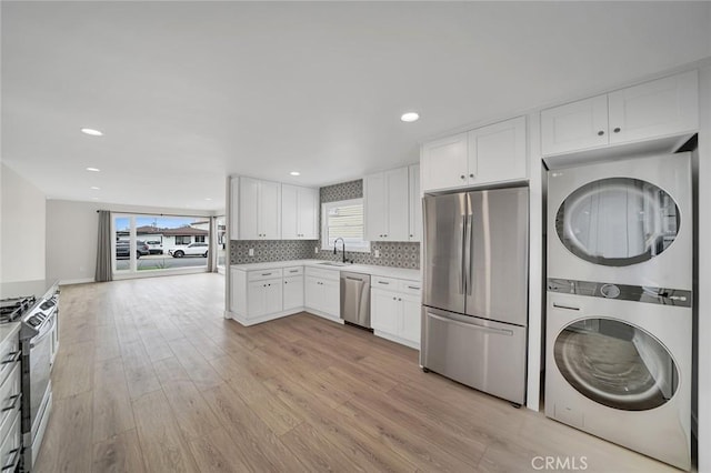 212 La Paloma, San Clemente, CA 92672 - kitchen with stainless steel appliances, stacked washer / dryer, light wood finished floors, white cabinetry, and light countertops