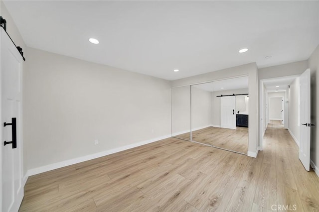 212 La Paloma, San Clemente, CA 92672 - unfurnished bedroom featuring a barn door, light wood finished floors, baseboards, recessed lighting, and a closet