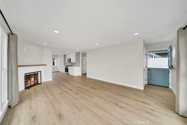 212 La Paloma, San Clemente, CA 92672 - unfurnished living room with light wood-style flooring, baseboards, a glass covered fireplace, and recessed lighting