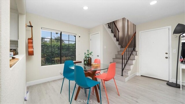 dining space with light wood finished floors, baseboards, stairs, and recessed lighting