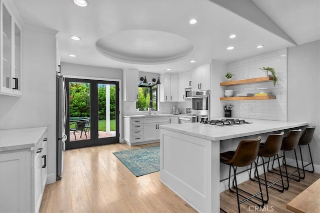 kitchen featuring a peninsula, appliances with stainless steel finishes, white cabinets, tasteful backsplash, and recessed lighting