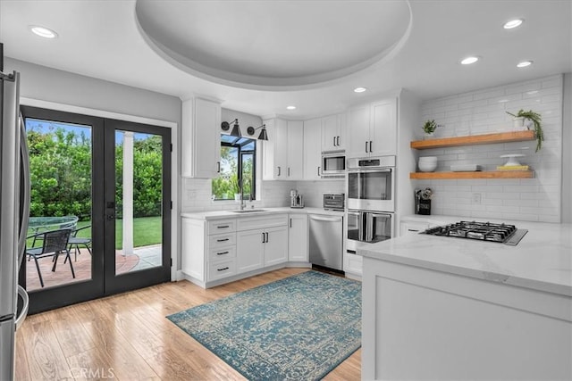 kitchen featuring french doors, appliances with stainless steel finishes, a sink, decorative backsplash, and white cabinets