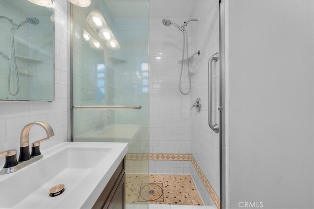 full bath with a shower stall, vanity, and tile walls