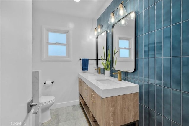 full bathroom with plenty of natural light, baseboards, toilet, and double vanity
