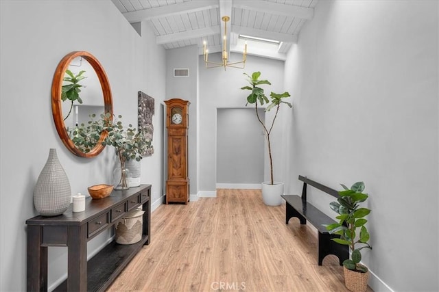 corridor with light wood finished floors, a chandelier, beamed ceiling, high vaulted ceiling, and baseboards